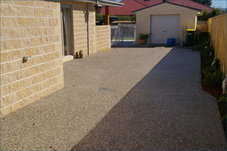 Residential photo of concrete pebble style concrete, driveway leading to rear garage.